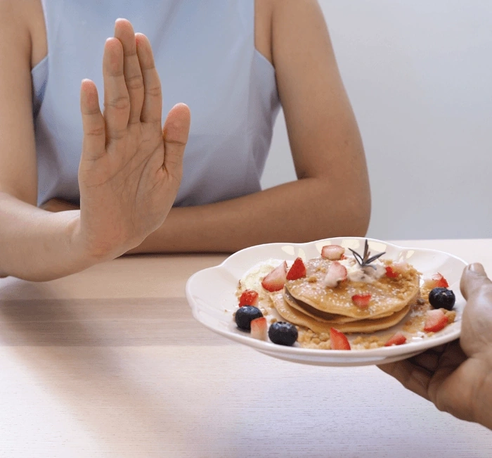 A person declining a plate of sweet pastries